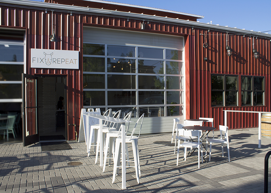 The red factory-exterior of the storefront and patio seating with white patio furniture